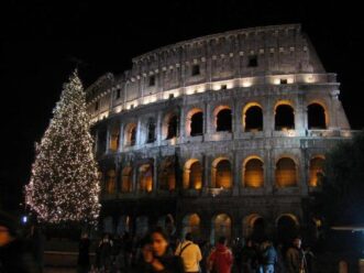 Italy - Colosseum lit up at night with people milling about at its base