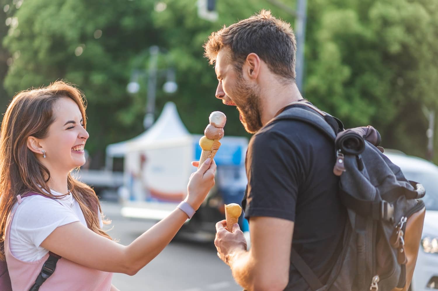 young woman feeding ice cream cone to young man