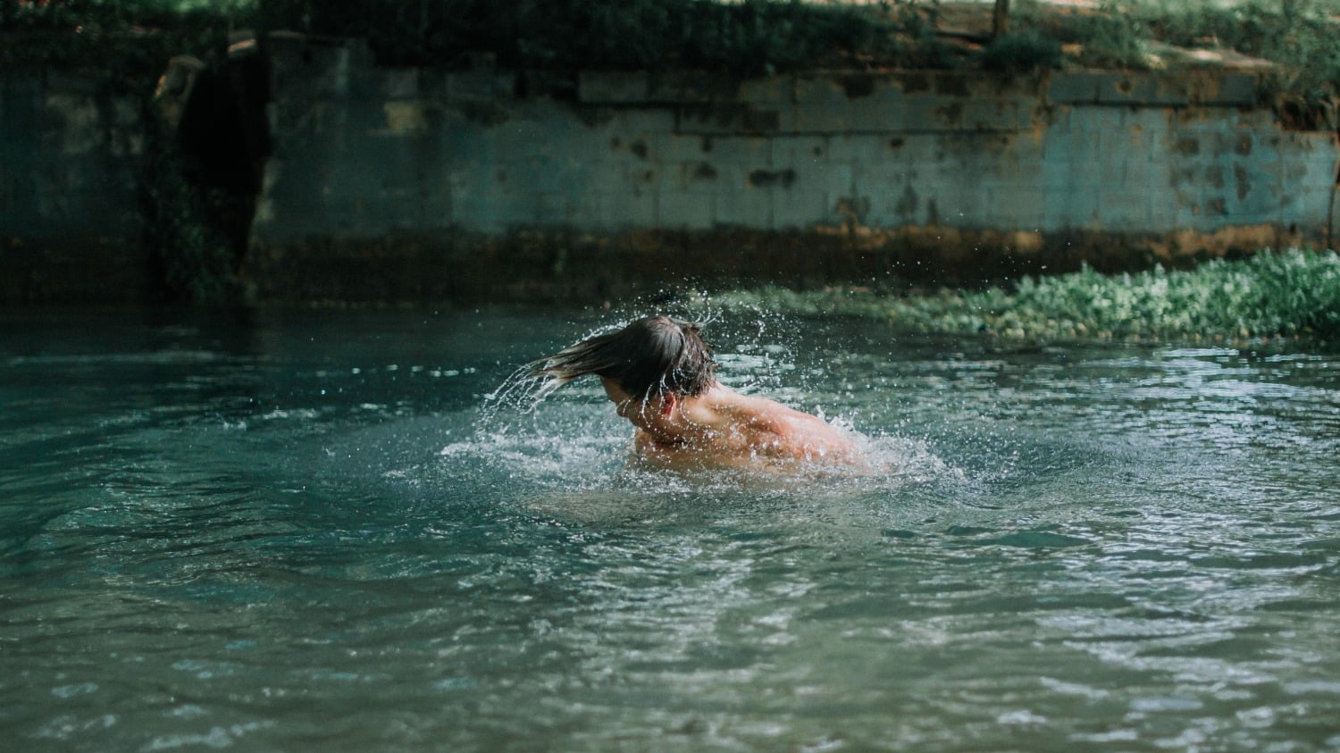 caucasian man in swimming hole shaking water off his head