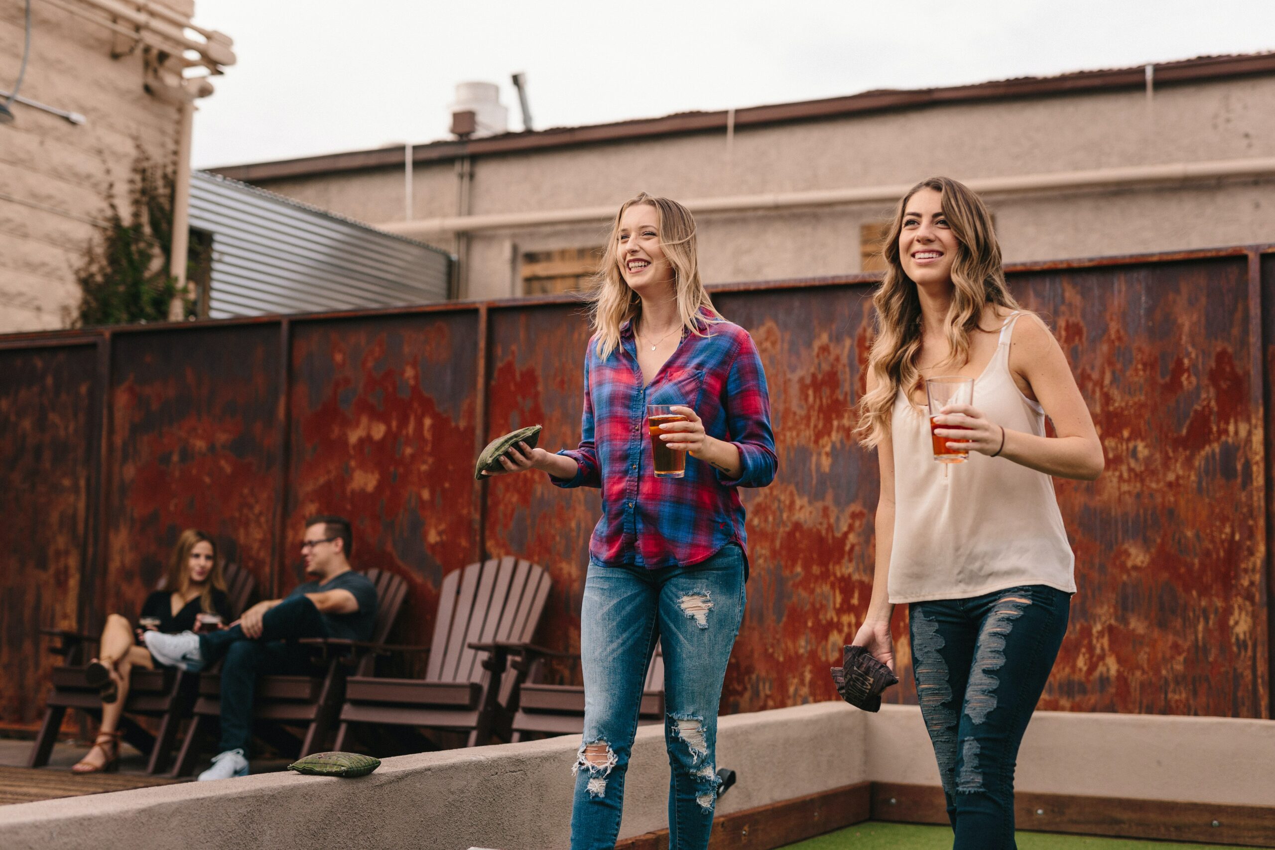 two white women playing cornhole on rooftop bar