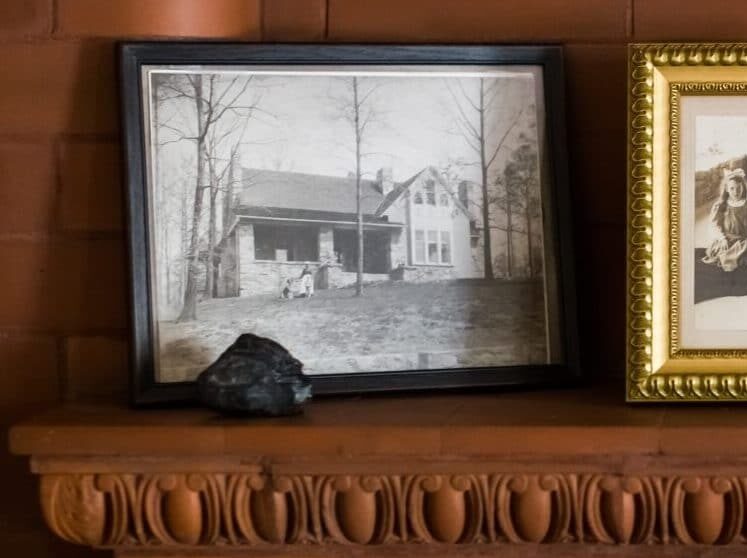 three black and white photos in frames on wood mantle