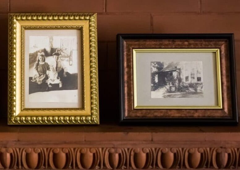 three black and white photos in frames on wood mantle