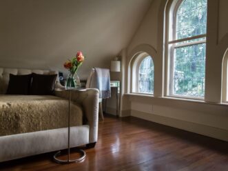 windows and daybed on wooden floors at The Eaves, a Stonehurst Place Guest Room