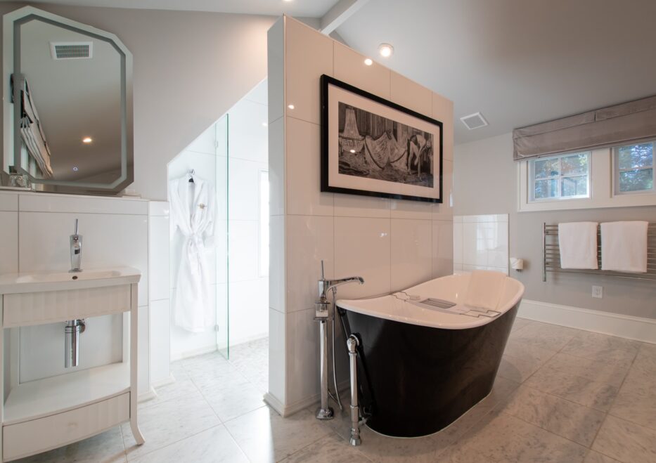 The Fowler room soaking tub with a small vanity and mirror above the sink