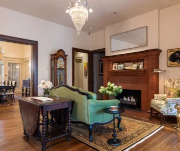 Elegant living room with fireplace, chandelier, green sofa, and wooden furniture.