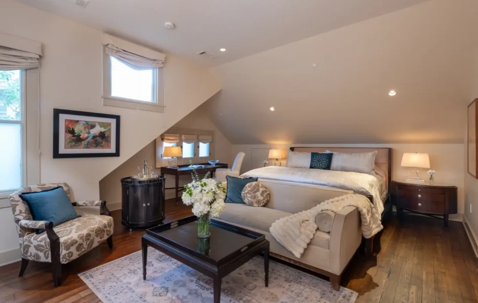 Cozy attic bedroom with slanted ceilings, furnished with a bed, sofa, and wooden decor.