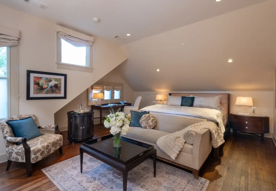 Cozy attic bedroom with slanted ceilings, furnished with a bed, sofa, and wooden decor.