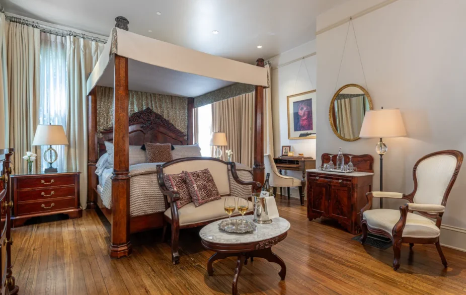Elegant bedroom with four-poster bed, sitting area, wooden furniture, and vintage decor.