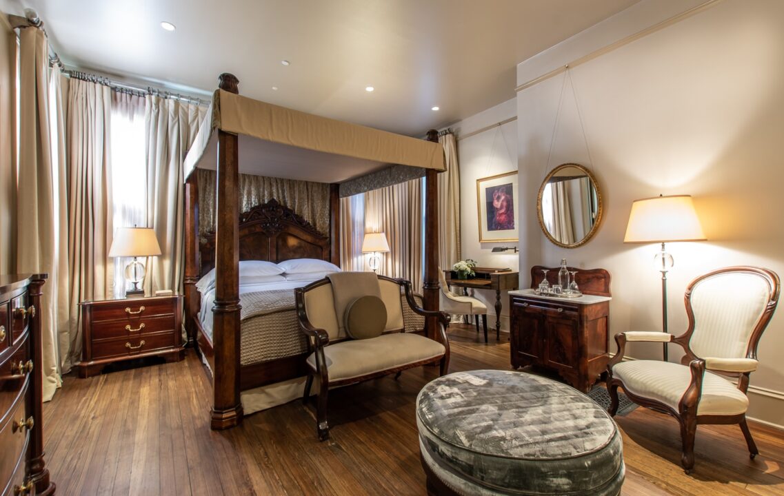 Hinman Suite with canopy bed and a sitting area with a velvet ottoman
