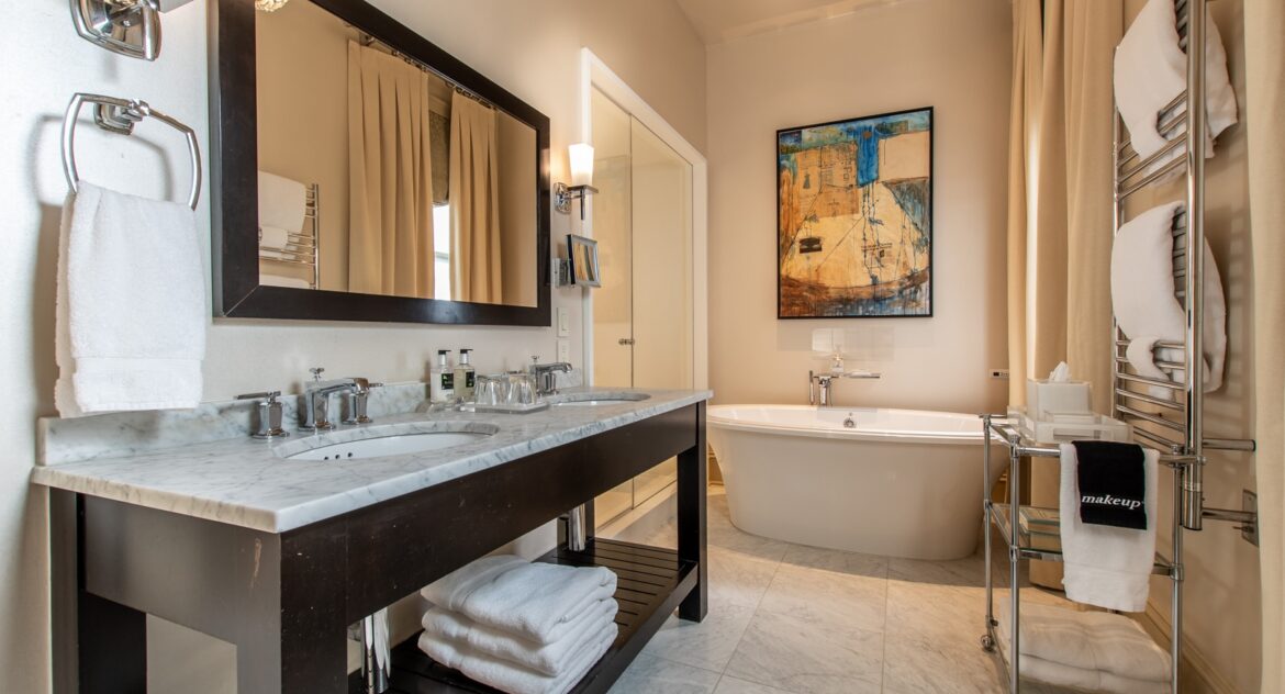Hinman Suite bathroom with double vanity sinks and a soaking tub