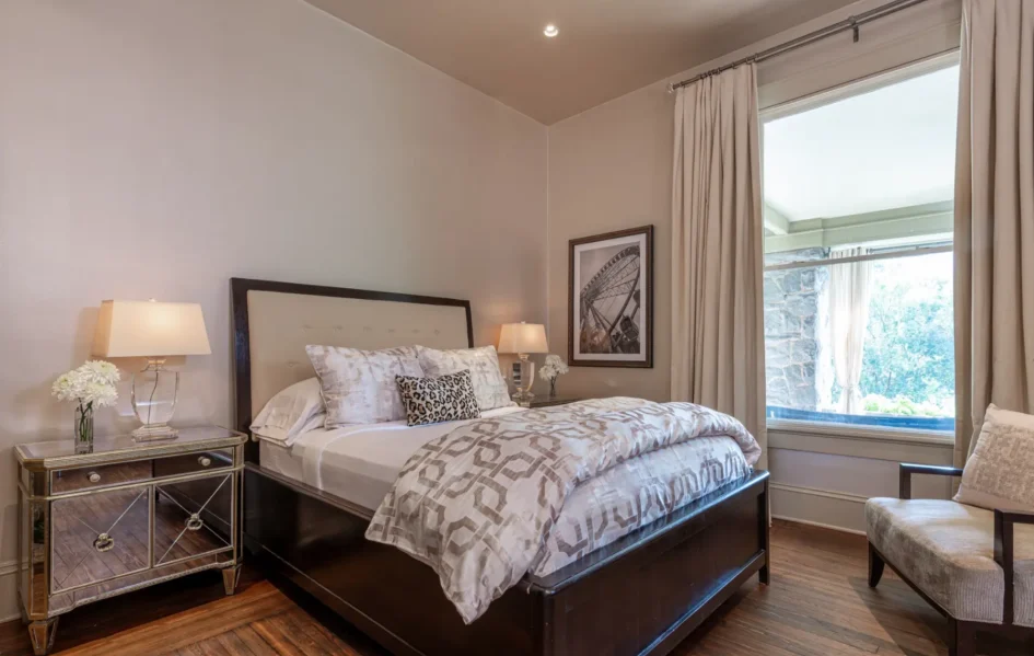 A cozy bedroom with a queen-sized bed, patterned bedding, side tables, lamps, and a framed picture.