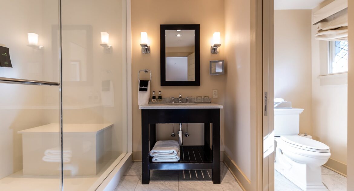 The Gables room bathroom vanity area with glass walk-in shower to the side