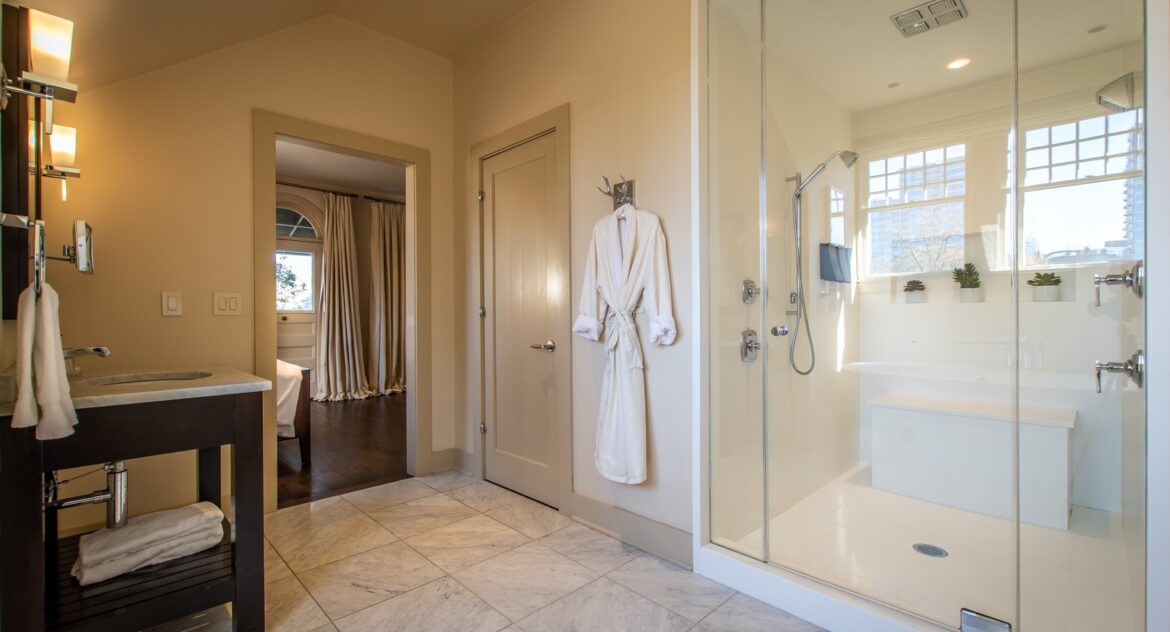 Master Suite bathroom with glass walk-on shower and a white robe hangin on the wall