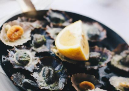 oysters and clams on black plate with lemon wedge