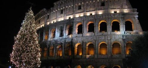 Italy - Colosseum lit up at night with people milling about at its base